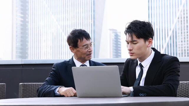 Two professional business partners shaking hands over a table with laptop after successful negotiation, iscussing good deal of trading to sign agreement and become a partner, property development deal