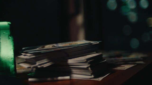 A cinematic close-up shot of stacks of US dollar bills neatly piled on a wooden desk, with soft urban bokeh lights and a green bottle in the background, symbolizing financial success
