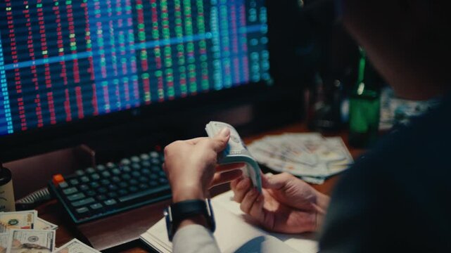 A cinematic shot of a modern trader's workspace, featuring multiple stacks of US hundred-dollar bills and real-time financial charts displayed on a monitor in the background.