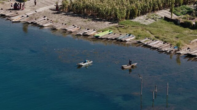 Two fishermen glide wooden canoes near shore on Lake Atitlan