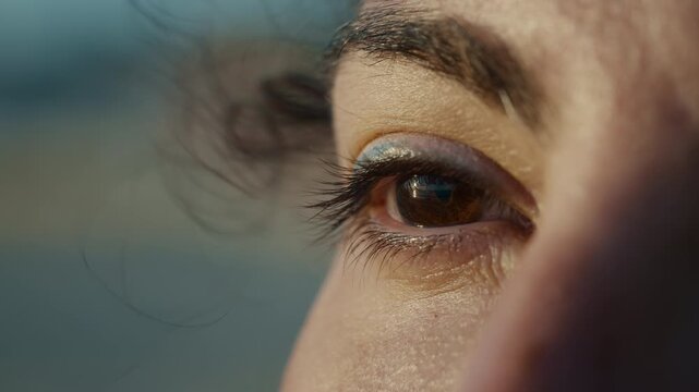 Macro close up of woman opening her eye at sunset on Sicily beach, wind in hair, gazing toward horizon, cinematic summer moment