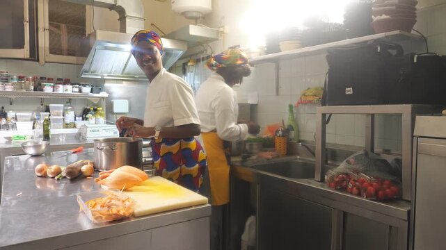 African women chefs cooking together in professional kitchen with cassava, yam and vegetable prep