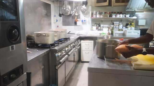 African women chefs cooking together in professional kitchen with cassava, yam and vegetable prep