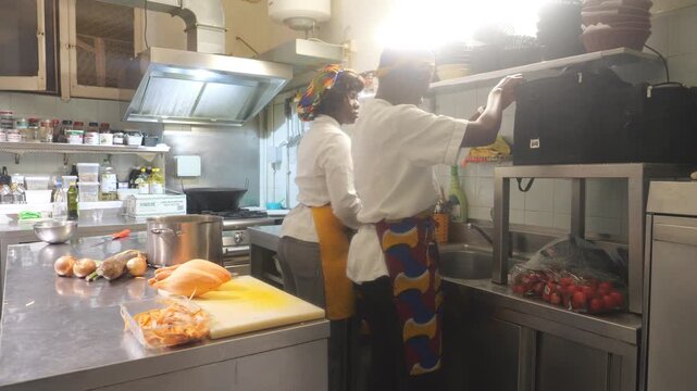 African women chefs working in professional kitchen preparing cassava, yam and vegetables for recipe
