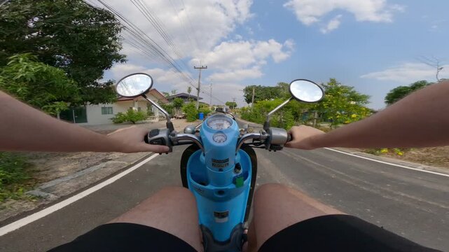 Chest POV view of scooter ride through a residential street in Thailand. Visible hands, handlebars and scooter body, captured with a wide angle action camera from rider perspective.