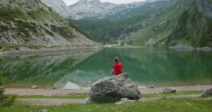 Woman Sitting On Rock By Alpine Lake Krn Slovenia In Summer Stillness