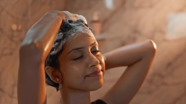 Female cleansing hair with shampoo while enjoying shower, showing beauty care