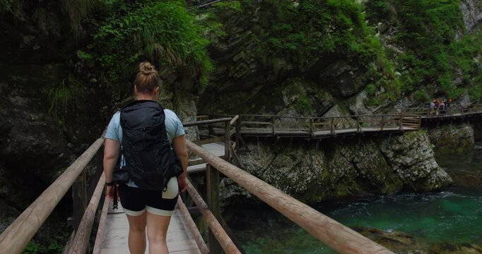 Female hiker crossing boardwalk above river in Vintgar Gorge