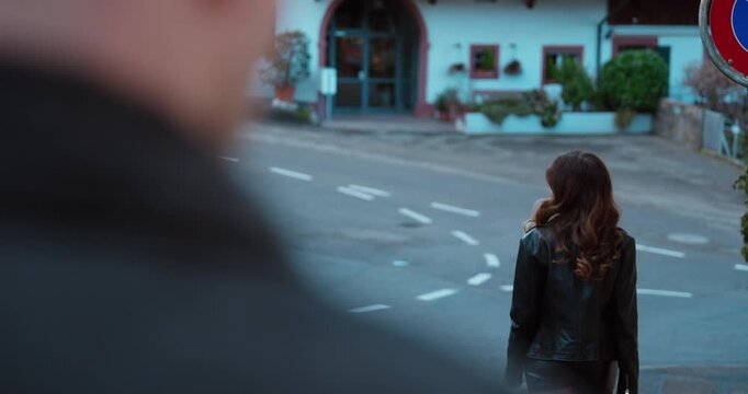 Outdoor scene of a woman turning back to look at a man before walking away. Concept of relationship conflict, farewell, emotional distance, rejection and breakup moment.