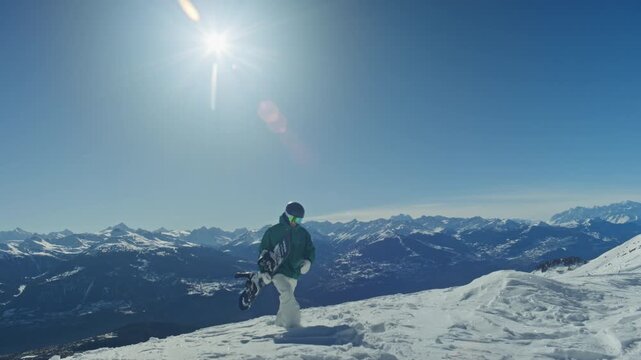 Snowboarder hiking uphill through snow with the Alps rising in the background. Human-powered ascent, adventure spirit, crisp winter light, and cinematic mountain lifestyle atmosphere.