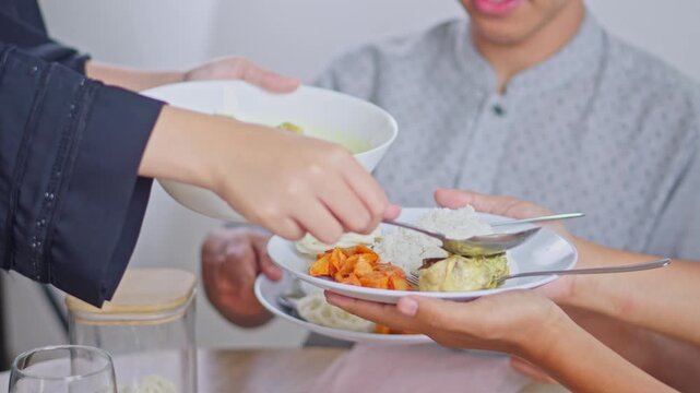Close up of muslim hands serving traditional Indonesian food on plates during Ramadan gathering
