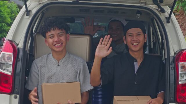 Group of friends waving goodbye from vehicle trunk celebrating Mudik holiday tradition