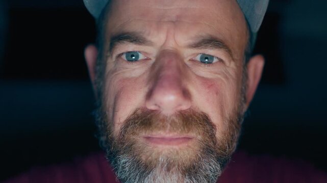 Direct eye contact with creepy man whose face is illuminated by digital screen