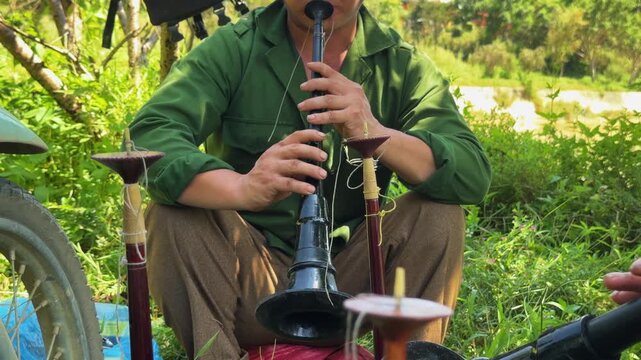 Local Hmong musicians play traditional instruments at the Bắc H&agrave; Sunday Market, captured against a backdrop of lush highland orchards and the authentic, colorful atmosphere of rural North Vietnam.