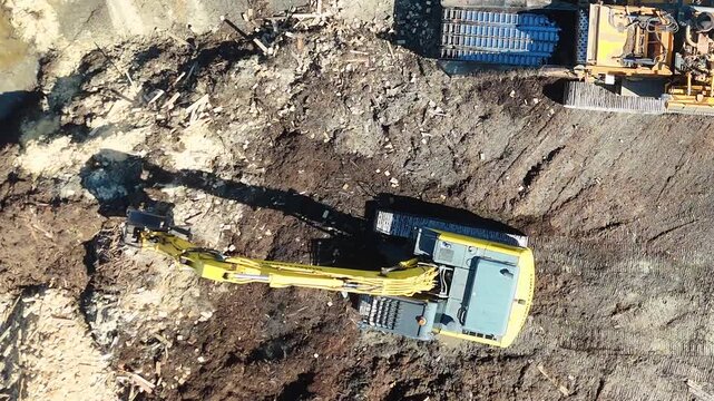 Top Down Aerial View of Yellow Excavator Moving Organic Mulch