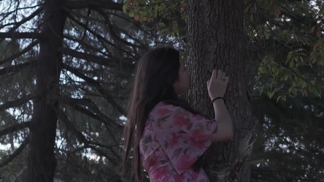 A Hispanic woman embraces a tree in Croydon Park, Melbourne. The scene captures a peaceful moment against a backdrop of lush greenery and soft, natural lighting.