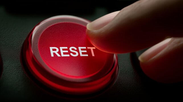 Finger pressing illuminated red reset button symbolizing restart, system restore, and fresh start.