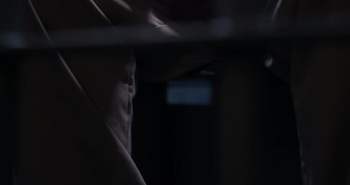 Close-up of prisoner's hands and legs as he nervously bounces his leg. The camera tracks right and pans left throughout the shot.