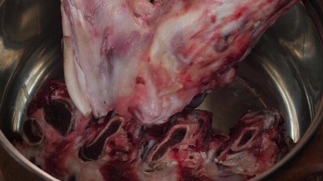 Raw beef bones are placed in a steel pot for cooking meat broth. Preparation of ingredients for making homemade soup or bone stock.
