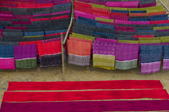 Narayanganj, Bangladesh - 08 March 2026: Aerial view of vibrant fabrics drying, their bold reds, pinks, and blues contrasting against the neutral ground, creating a colorful tapestry.