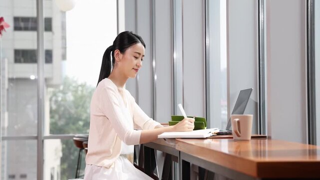 Portrait business woman using a laptop computer to work online, taking notes notes in her diary looking up into the distance, woman corporate typing, sending emails, checking things off her to do list