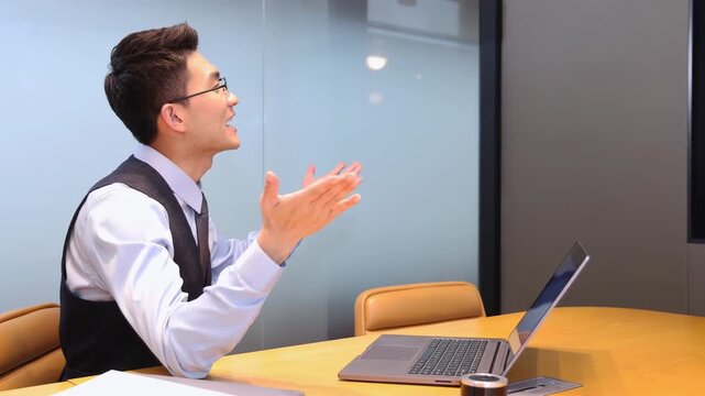 Confident businessman in formal suit using computer technology app holding a video conference in a meeting room to cheering with a group of colleagues or employees working together in a modern office