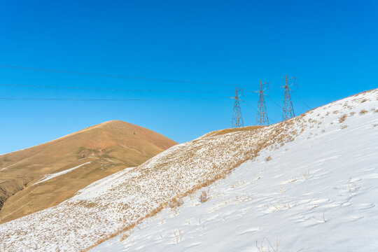 Three electricity transmission towers on a snow-covered hillside in the Western Tian Shan, Uzbekistan