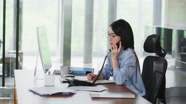 Focused busy young entrepreneur business woman with glasses typing on laptop computer, hurry specialist answering call and hands taking notes on paper documents. Female employee interrupted at work