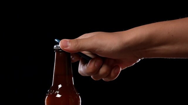 Unrecognizable male hand opening cold bottle of beer, foam rising overflowing. Hands cracking refrigerated wheat or lager beer with an opener isolated on black background banner with copy space