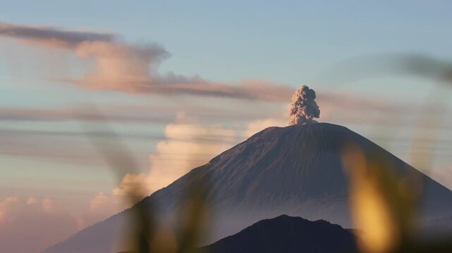 Wide shot of Sunrise Eruption of Mount Semeru Framed by Foreground Silhouettes from King Kong Hill in East Java , Indonesia
