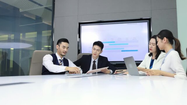Group of colleagues having a work meeting in the boardroom, sitting around the office table, listening to a male speaker making a presentation and taking notes on new marketing strategies