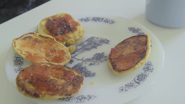 Close-up of a child's hand taking and returning a bitten pancake. Natural color grade and sharp food textures in a 2026 style.