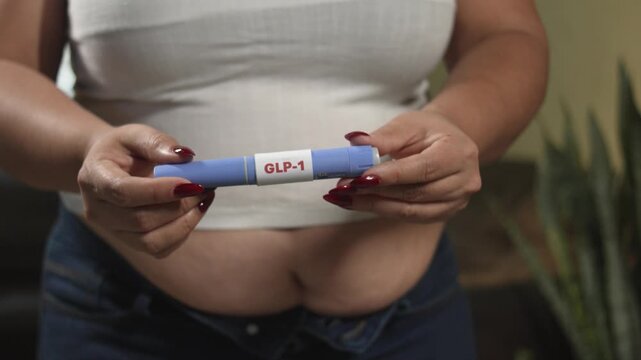 Overweight woman holding a GLP-1 injection pen at home, weight control and insulin resistance care