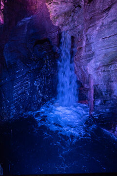 Cascate Varone small waterfall with blue light inside rock cave with flowing water and textured walls in parco grotta Italy