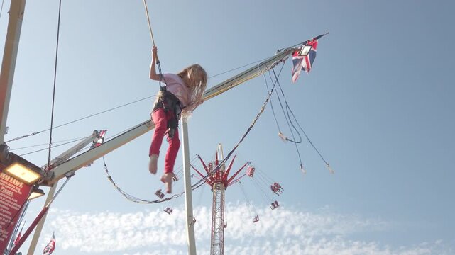 Static wide shot of a child on a bungee trampoline ride in Paignton, UK. Natural light