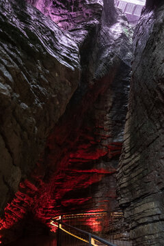 Cascate Varone gorge with red light illuminating layered rock walls in underground cave parco grotta Trentino Italy