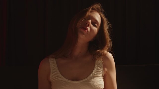 Beautiful portrait of an attractive woman wearing a tight bralette sensually waving her hair in slow motion