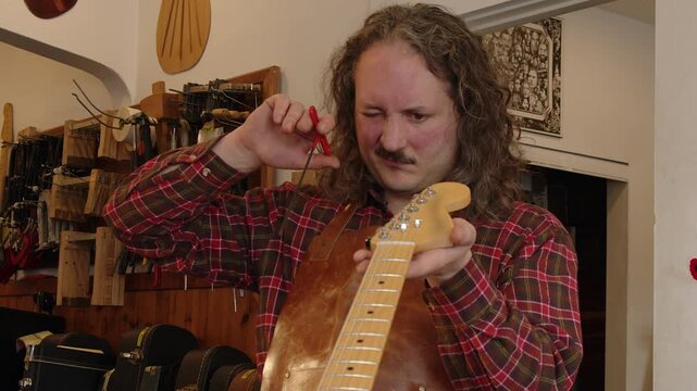 Technician in shop adjusts truss rod in neck of vintage electric guitar