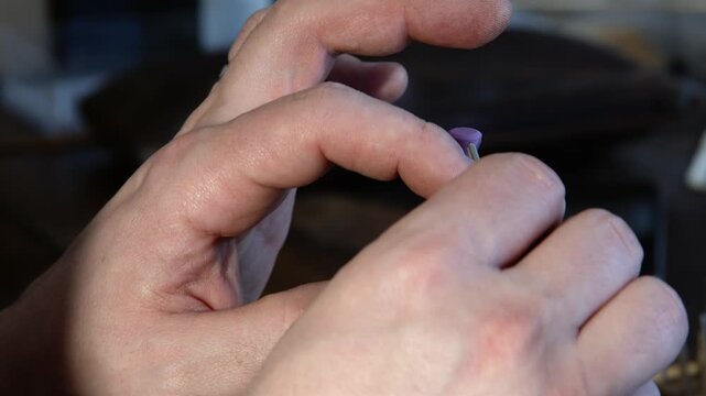 Guitar tech at bench uses grinding tool to shape fret for guitar, CU