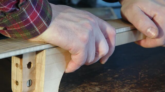 Closeup: Maple fretboard is placed on wooden guitar neck blank in shop