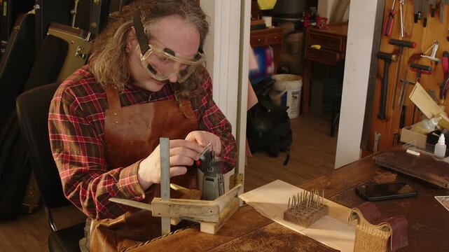 Guitar tech luthier grinds tang, shapes fret for guitar at work bench