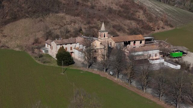 Sant Ilario Vescovo parish church and rural buildings in Chiavenna Rocchetta near Lugagnano Val d'Arda, Piacenza Province, Emilia-Romagna, Italy surrounded by farmland hills