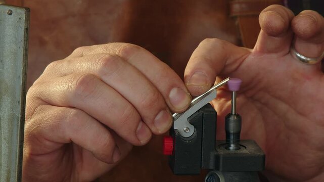Low angle closeup: Guitar tech grinds tang from guitar fret in shop