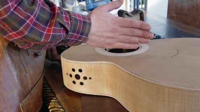 Luthier at work bench demonstrates bookmatch joint on acoustic guitar
