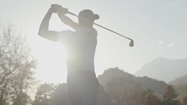 Tight shot of a golfer swinging in Sion, Switzerland with the sun behind the player creating strong lens flares. Dramatic lighting, focused motion, and cinematic golf action.
