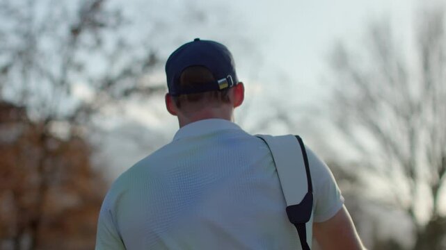 Golfer walking across the green carrying a golf bag in Sion, Switzerland. Calm moment on the course with scenic alpine surroundings and authentic golf lifestyle atmosphere.