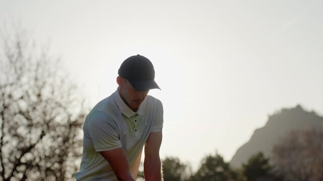 Tight shot of a golfer swinging in Sion, Switzerland with the sun behind the player creating strong lens flares. Dramatic lighting, focused motion, and cinematic golf action.