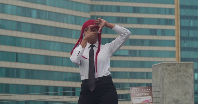 A girl in a white corporate shirt and black slacks overlooks a colorful colonial city from a rooftop, her red hair catching the sea breeze.