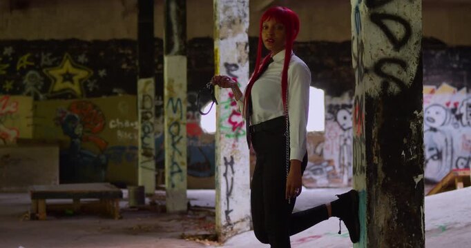 A stylish red-haired girl in a white shirt and black pants walks through a skate park where the concrete is alive with layers of urban street art.