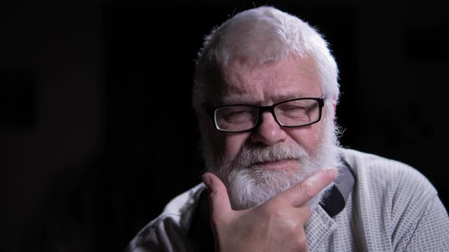 Noble man wearing glasses, gray hair and a beard, lost in thought